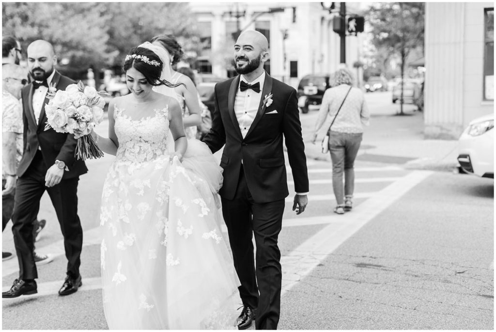 A bride and groom walking across the street for their wedding photos