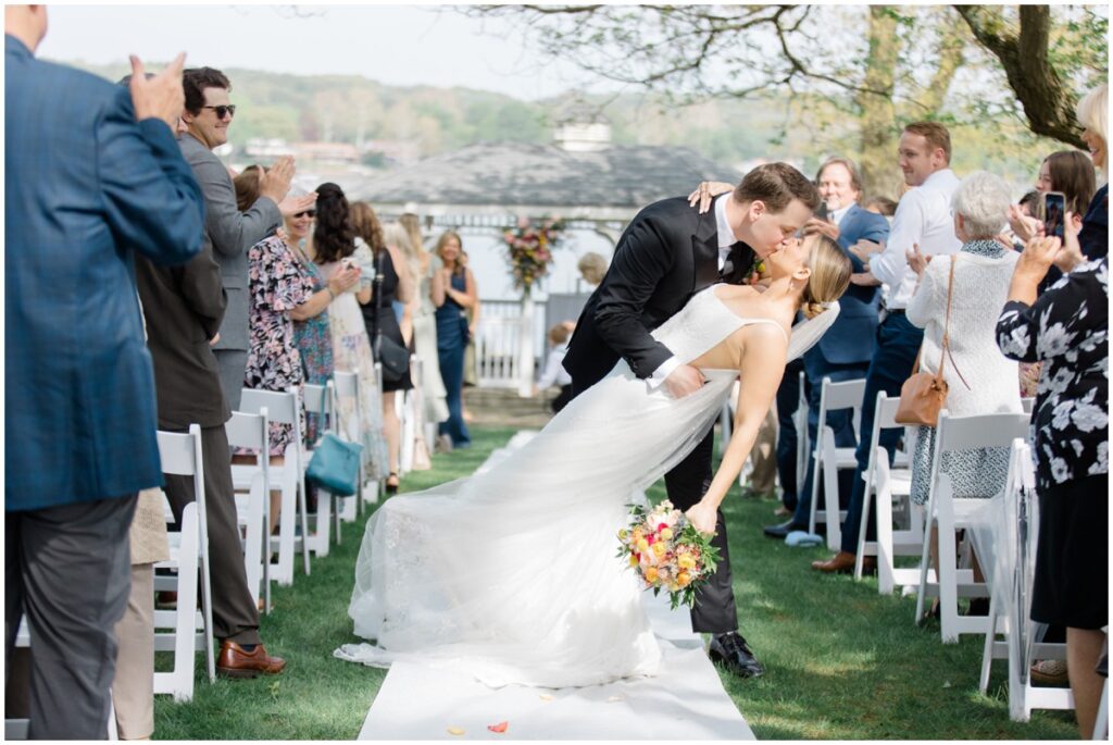 a groom dipping his bride for a kiss in the isle at the Tudor house at mason's cove