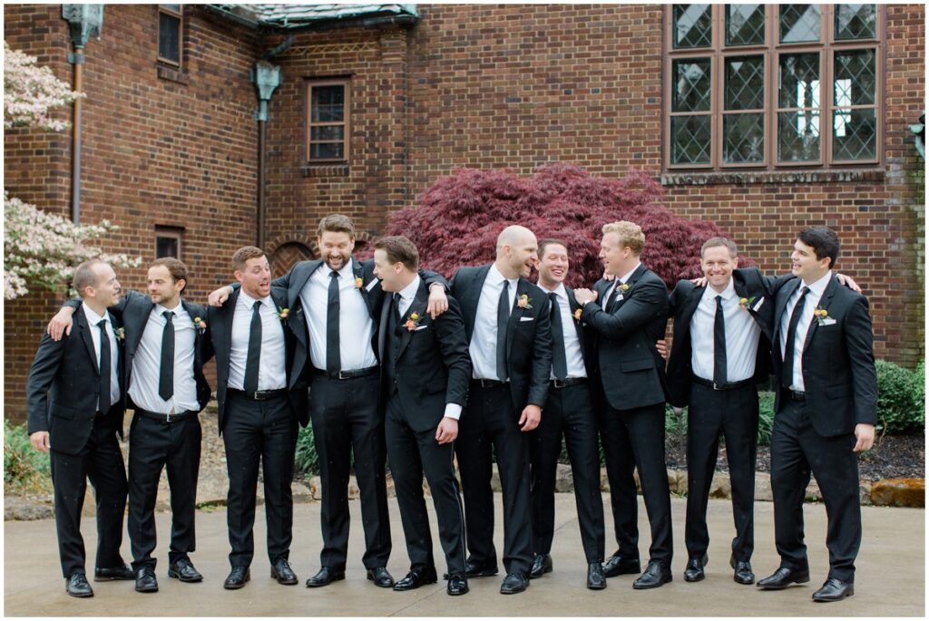 a groom and his groomsmen posing in front of the Tudor house at mason's cove wedding venue