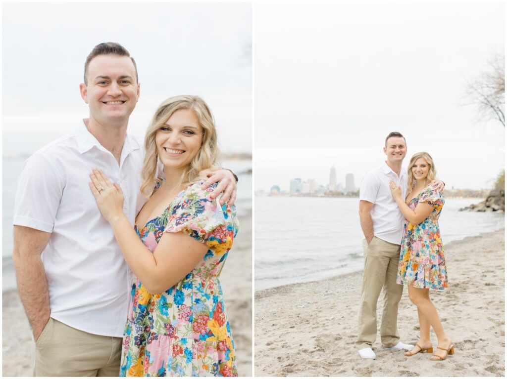 An engaged couple posing at Edgewater park for their engagement session with the cleveland skyline behind them