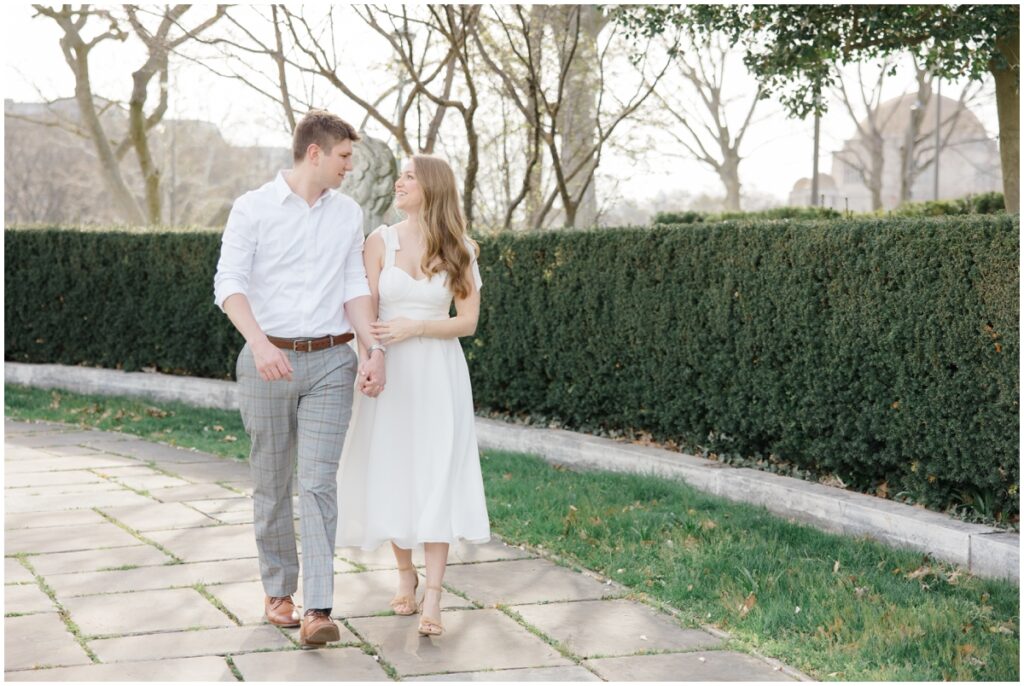 An engaged couple walking and smiling at each other at the Cleveland Museum of Art