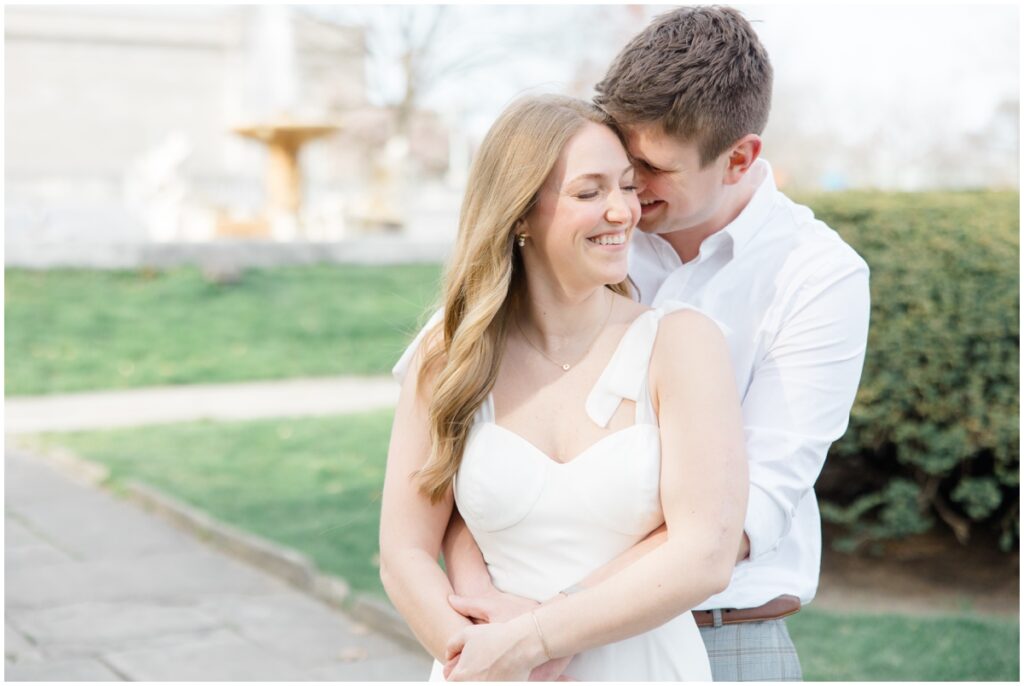 A couple laughing and smiling while holding each other during their engagement session at the cleveland museum of art