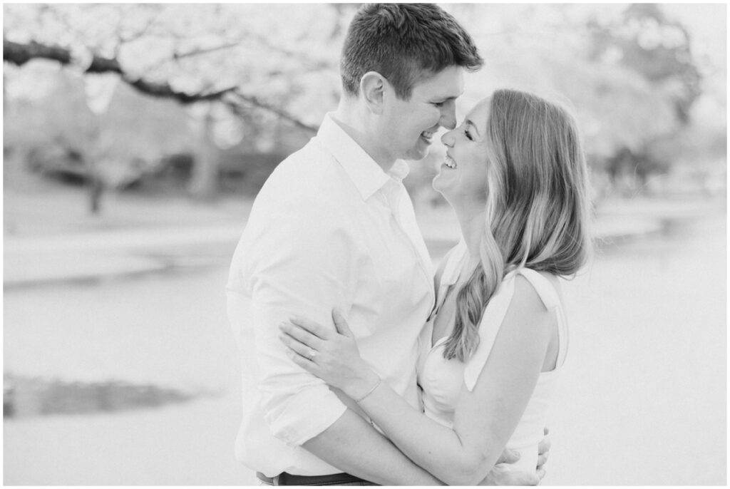 A couple looking at each other under cherry blossom trees during a spring time engagement session at the cleveland museum of art