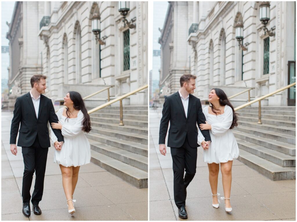 A couple walking and laughing while holding hands in front of the Cleveland Public Library during their engagement session.