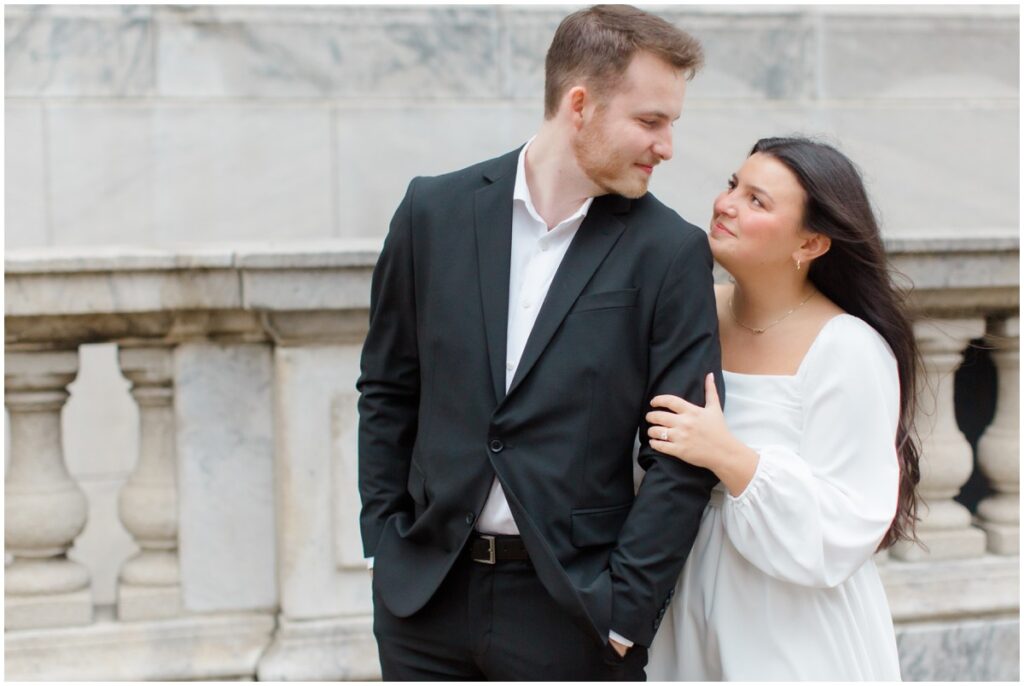 A couple embracing each other in front of the Cleveland Public Library during their engagement session in Cleveland, Ohio.