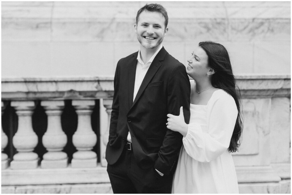 A couple embracing each other in front of the Cleveland Public Library during their engagement session in Cleveland, Ohio.