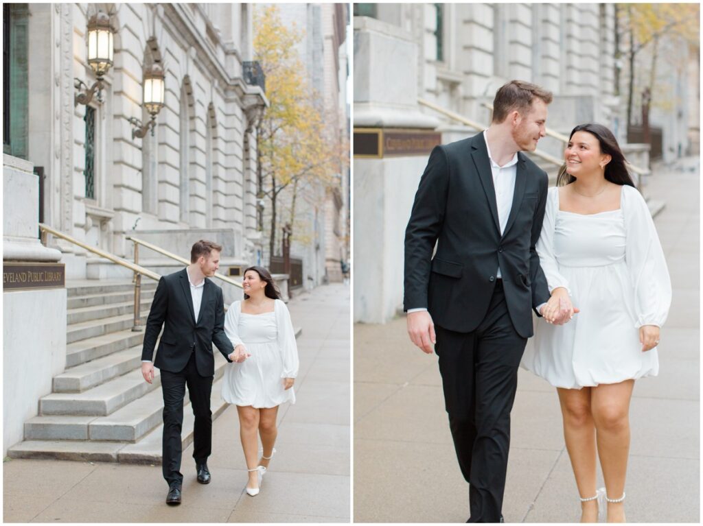 a couple holding hands and walking for their engagement session photos in front of the Cleveland Public Library