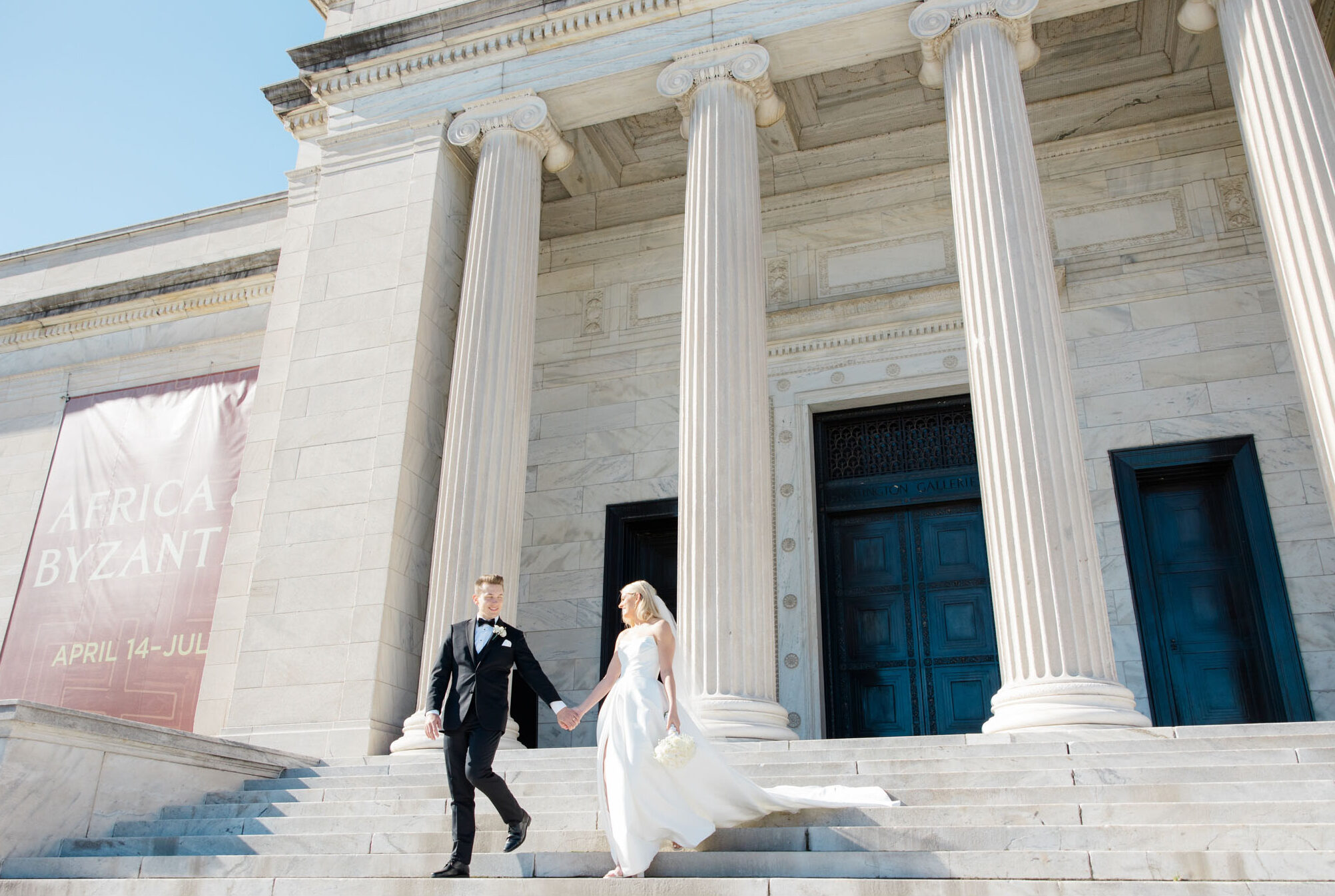 bride and groom walking down the steps in front of the cleveland museum of art
